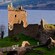 Las ruinas del castillo en una colina cubierta de hierba con vistas a una masa de agua